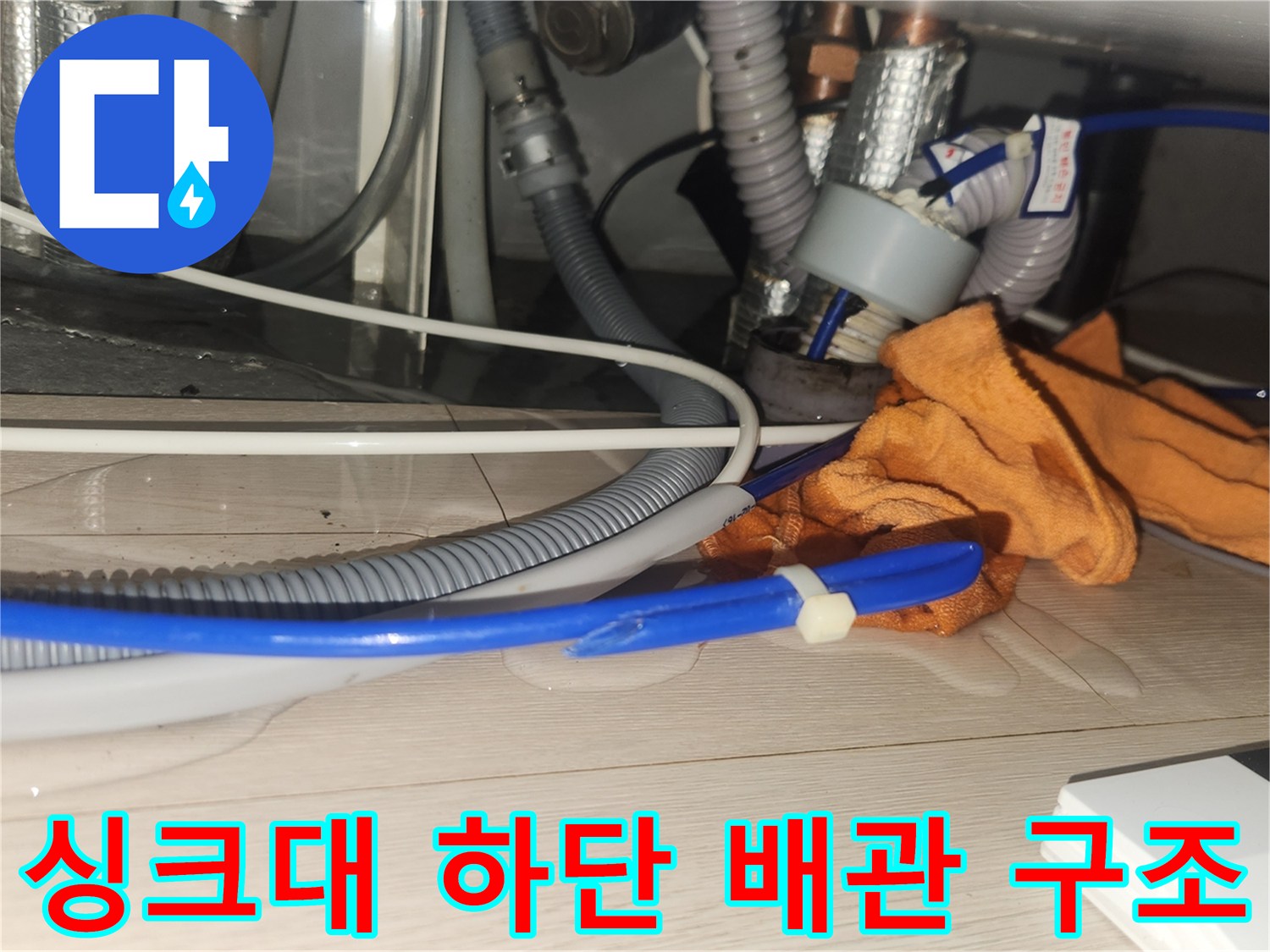 주방 싱크대 하부-복잡하게 연결된 배수 호스와 금속 배관들