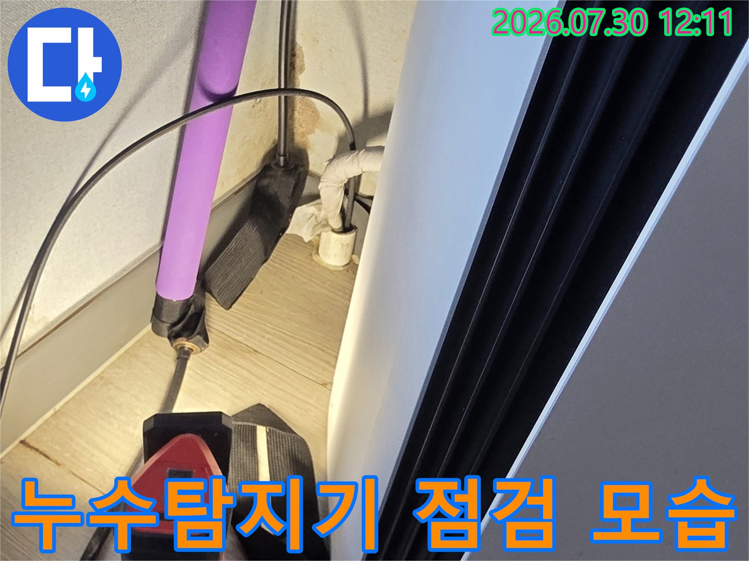 세탁실 배관 부근에서 누수 탐지기를 사용하여 공기압을 체크하는 장면