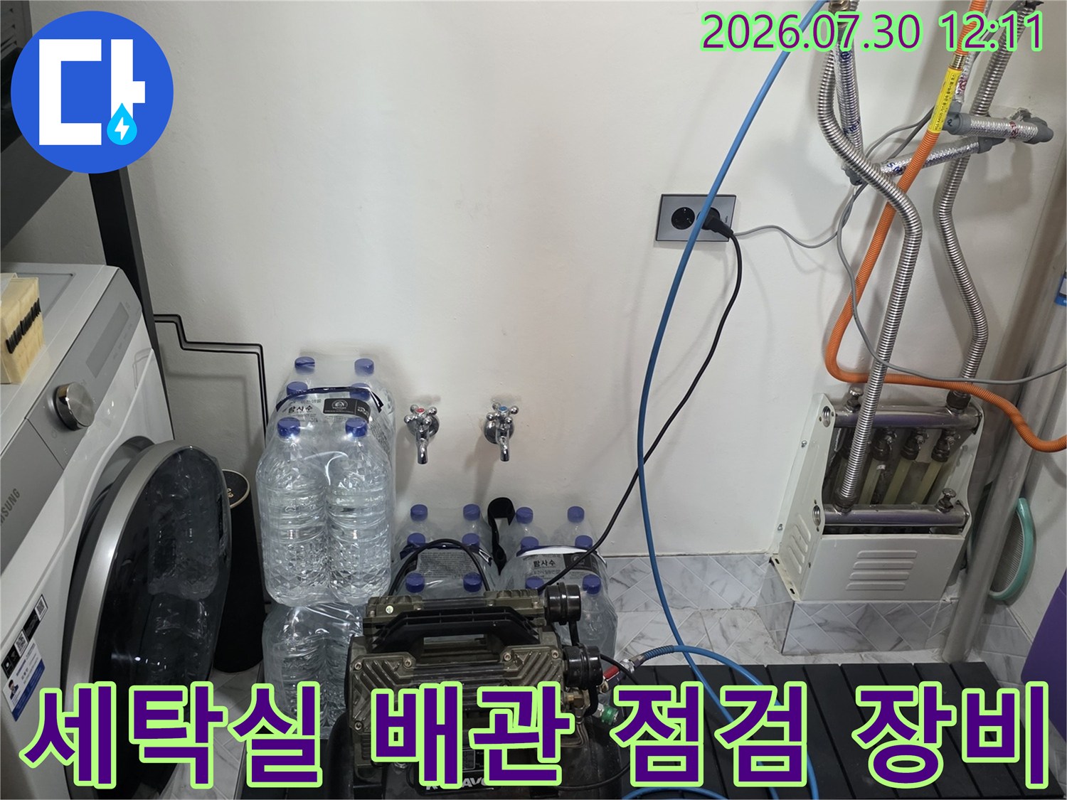 전문가용 게이지와 호스를 연결하여 세탁실 내 배관 시스템을 정밀하게 테스트하는 모습