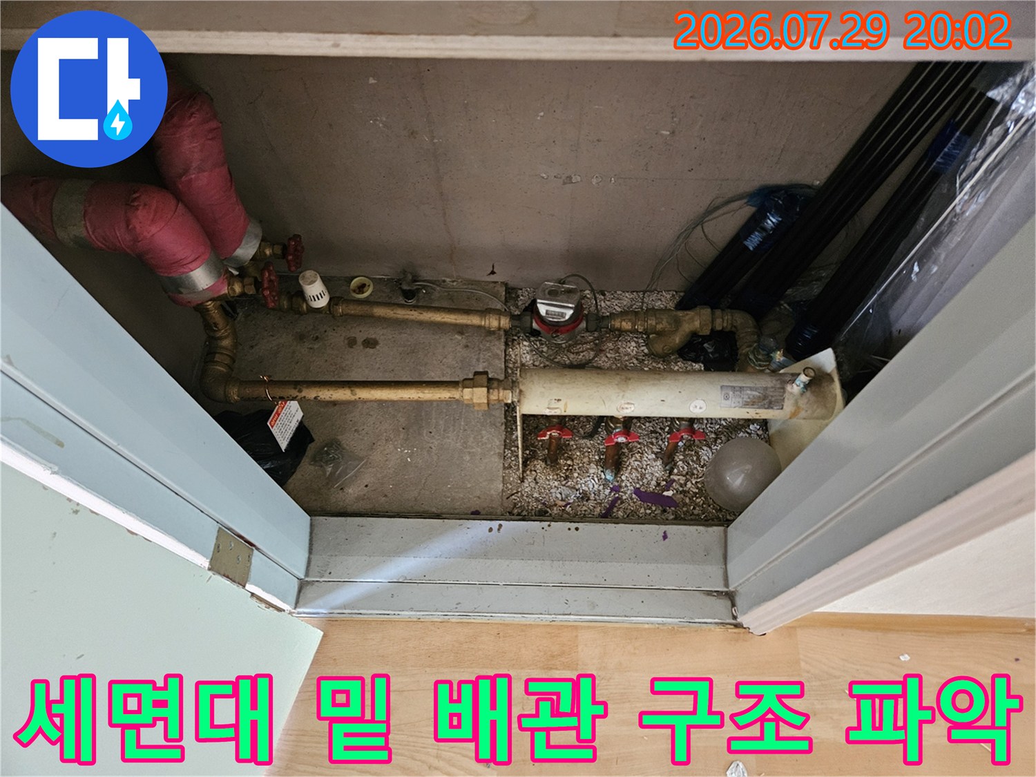 세면대 하단에 위치한 다수의 수도배관과 연결부를 정밀하게 진찰하는 모습