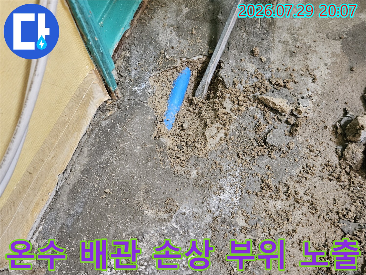 노란색 바닥재 아래 파란색 온수 배관의 누수 구간을 촬영한 사진
