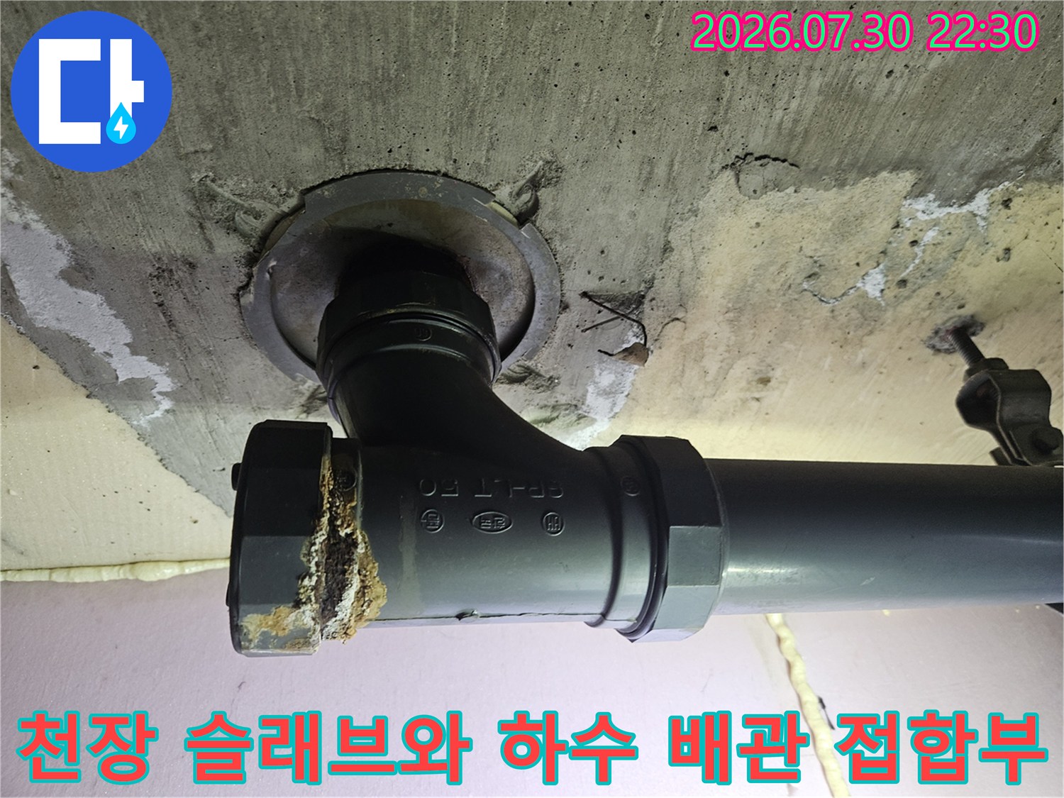 콘크리트 천장과 연결된 검정색 하수 배관의 세밀한 점검 모습