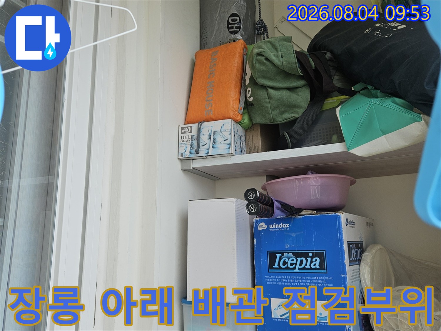 장롱 밑 공간에 노출된 각종 물품과 배관이 섞여 있는 모습