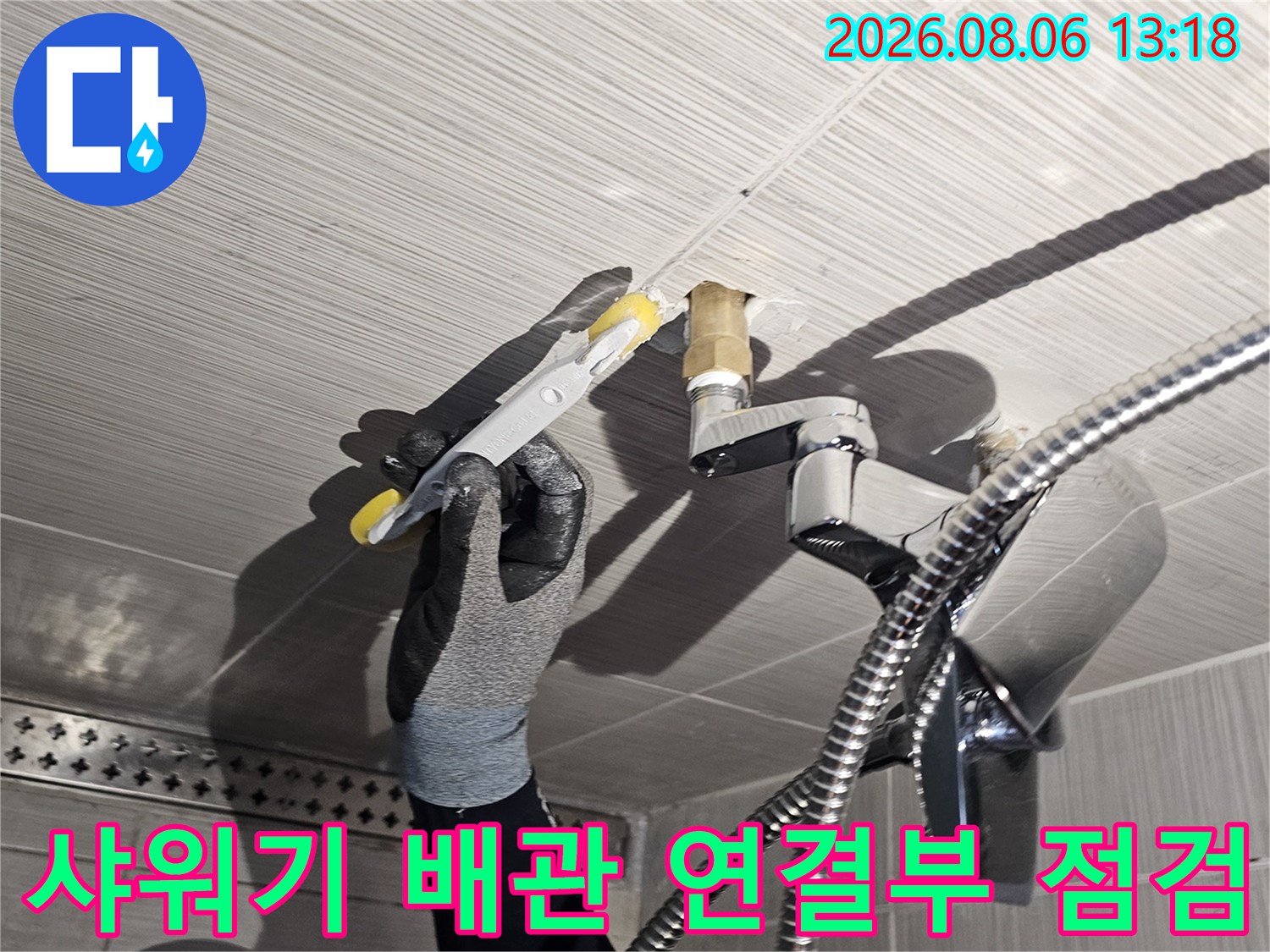 샤워기 수전과 연결된 금속 배관 부위를 세밀하게 점검하는 모습
