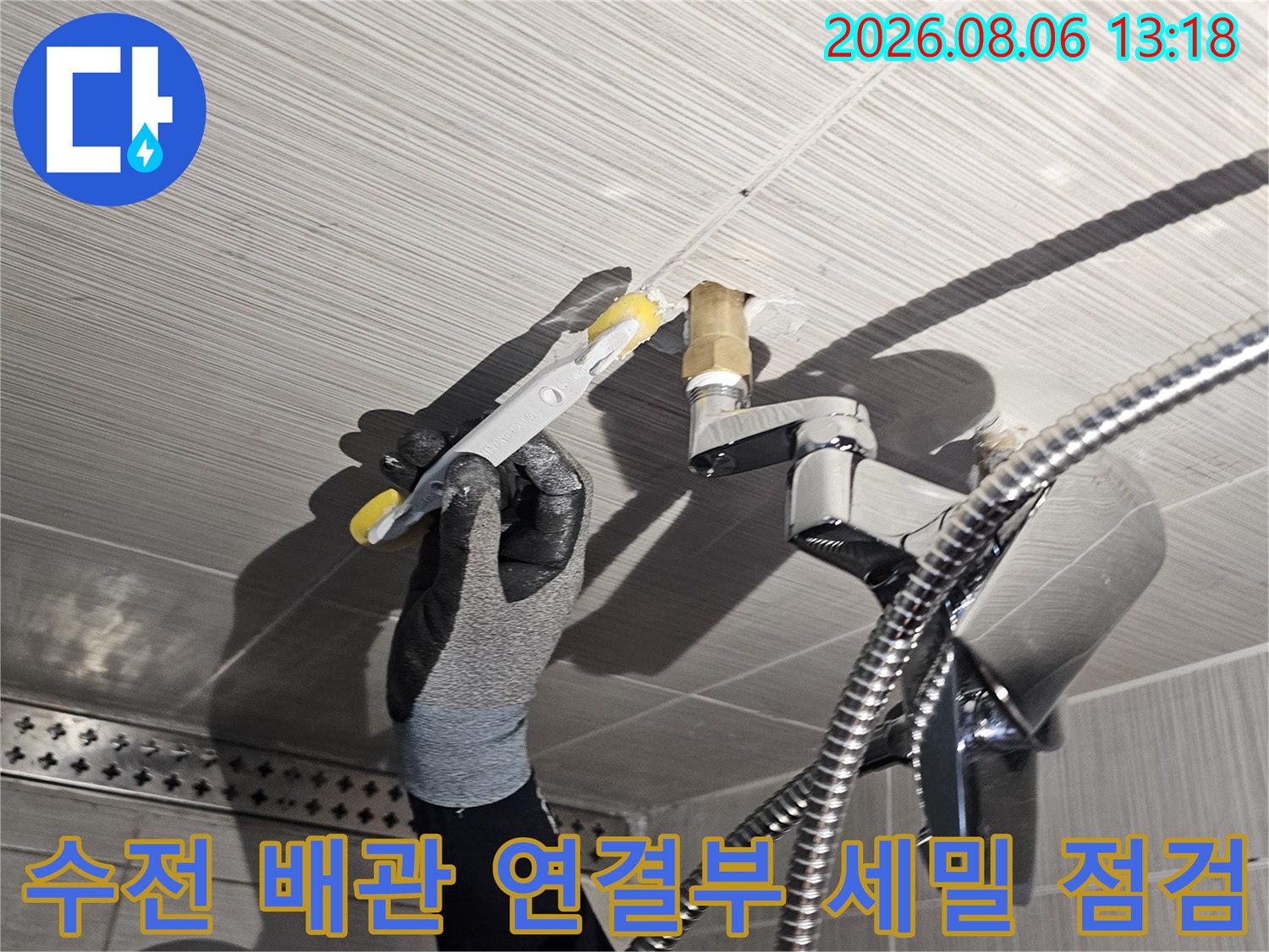 장갑을 낀 전문가가 수전과 연결된 금속 배관 부위를 정밀히 진단하는 장면