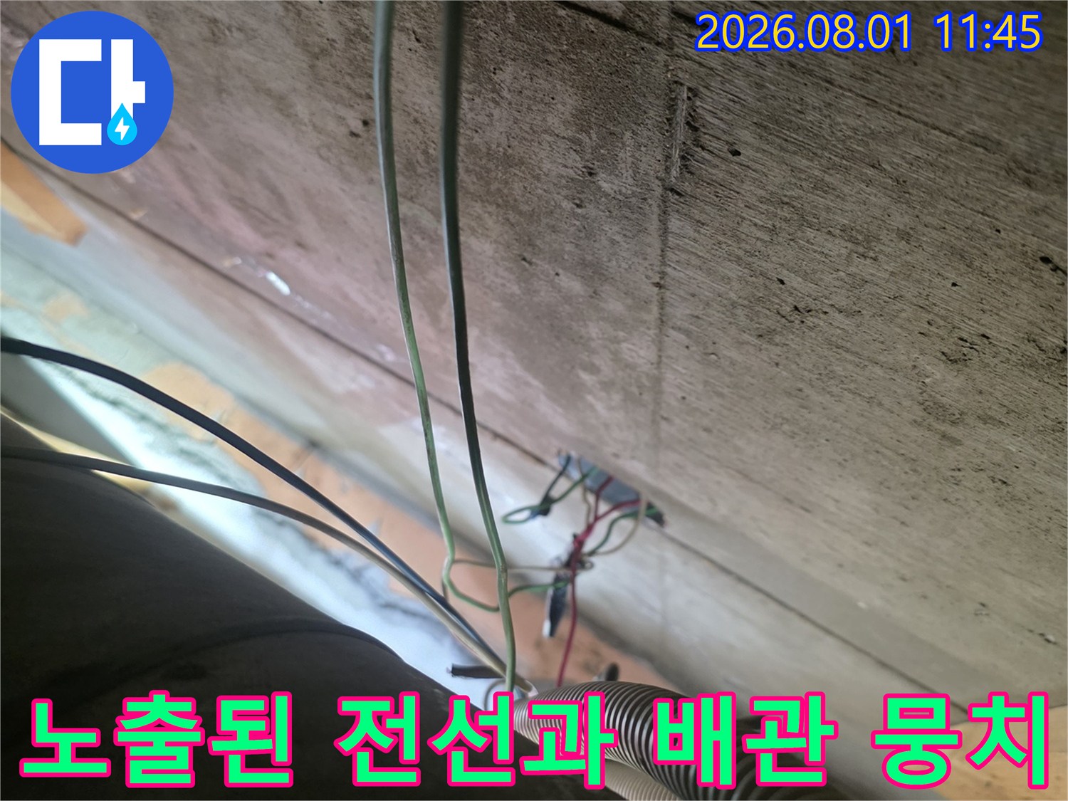 전선과 배관이 복잡하게 얽힌 천장 내부의 노출 구간을 촬영한 사진입니다.