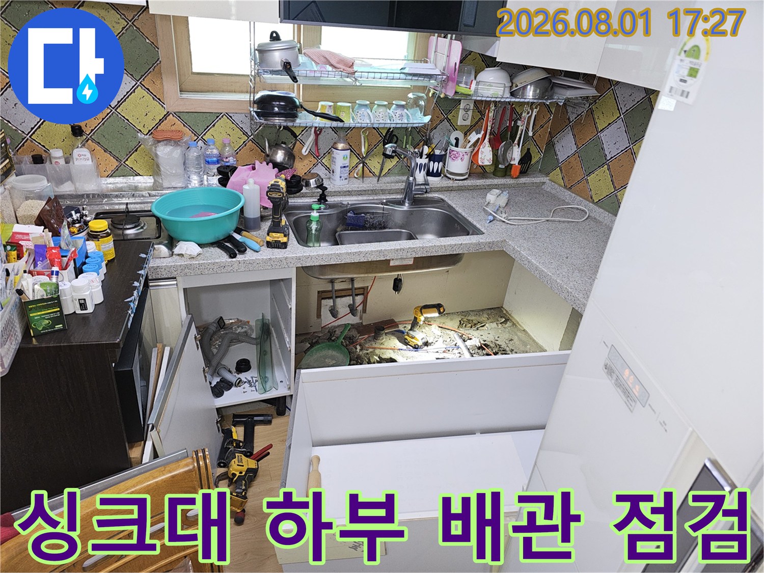 싱크대 아래 공간에서 노출된 배관의 누수 여부를 확인하는 현장 모습