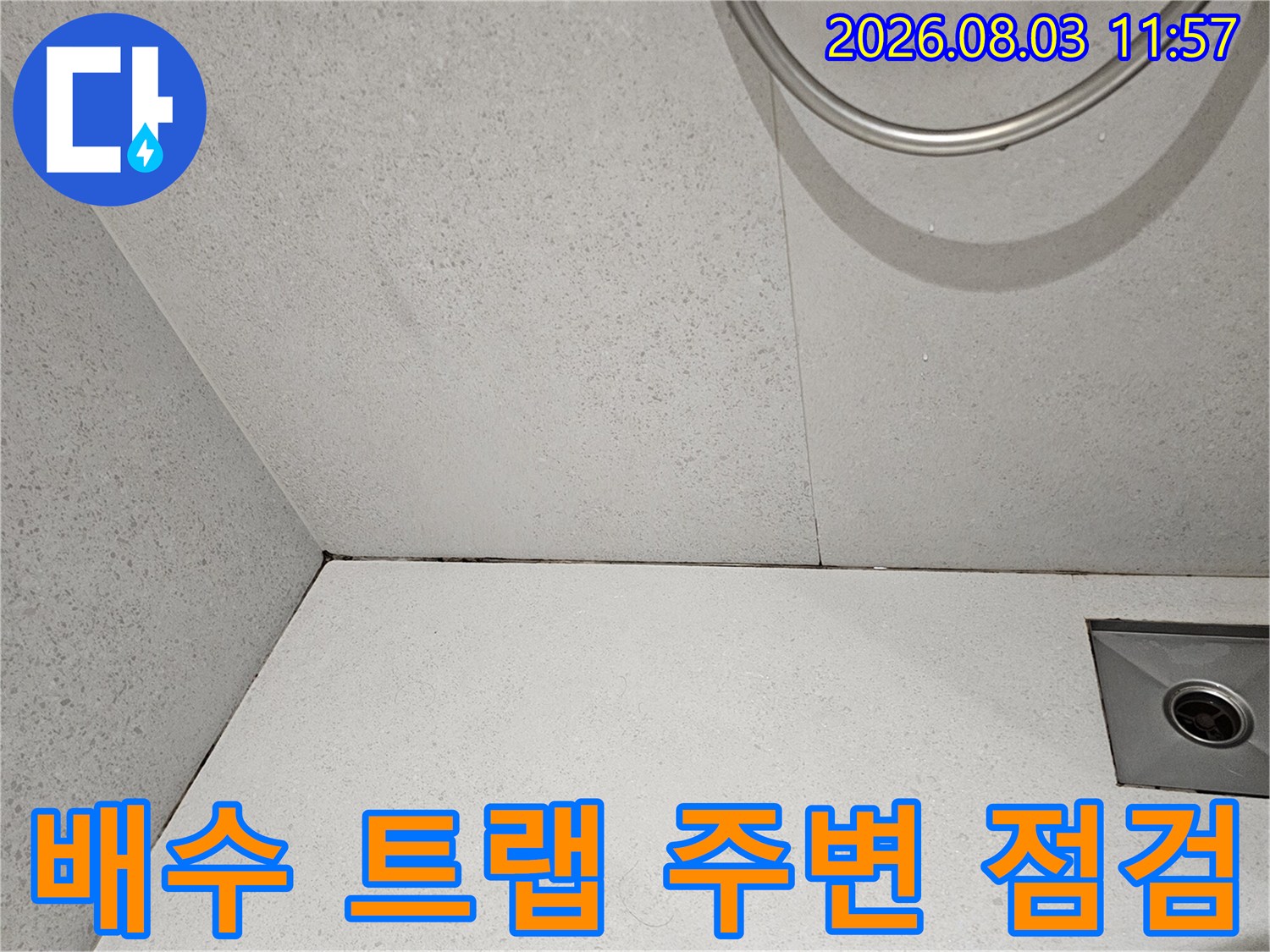 금속 재질의 배수 트랩과 주변 타일면을 촬영한 사진