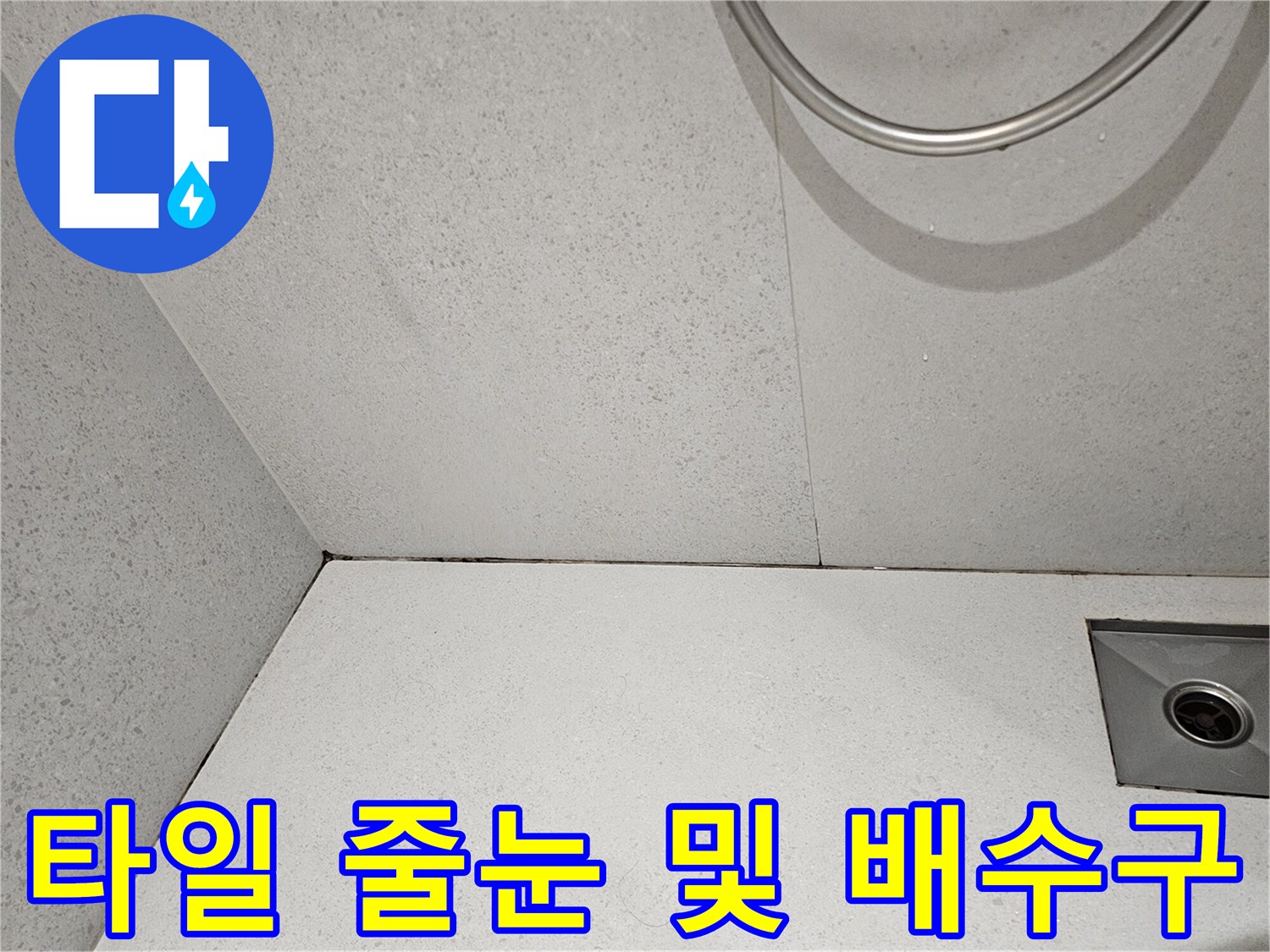 배수구 주변 타일 틈새와 벽면 접합부를 근접 촬영한 이미지입니다.