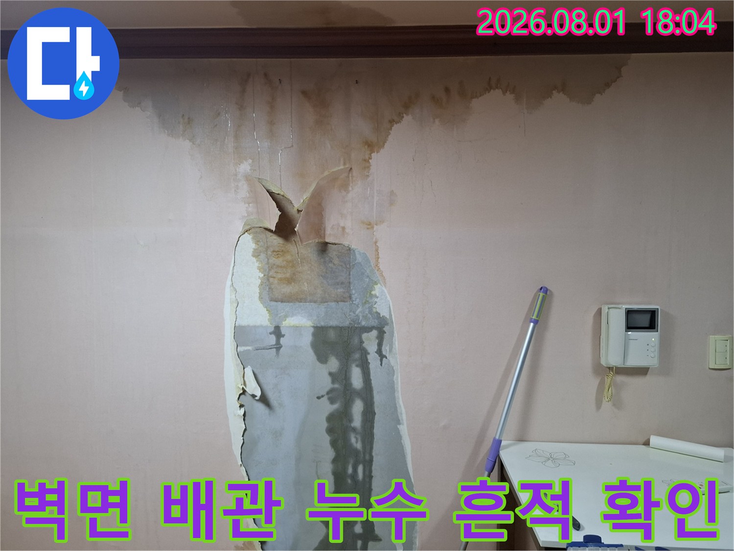 벽면에 발생한 누수 얼룩과 훼손된 벽지 내부의 배관 노출 부위