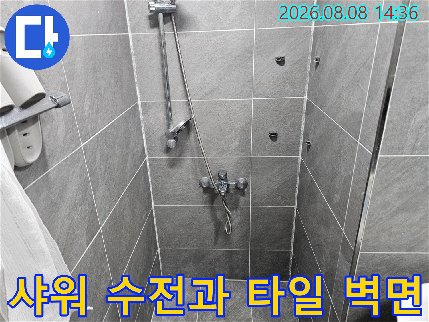 벽면에 설치된 샤워기 수전과 회색 타일의 모습입니다.