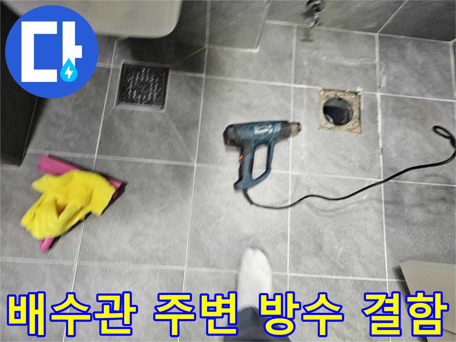 타일 바닥 오수관 입구의 노출된 배관과 파손된 틈새