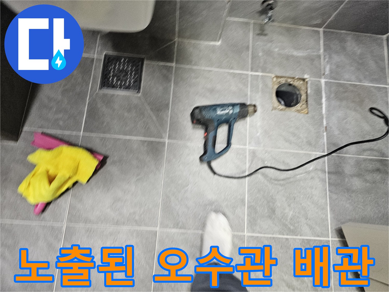 타일 바닥에 노출된 오수관과 주변 작업 도구들