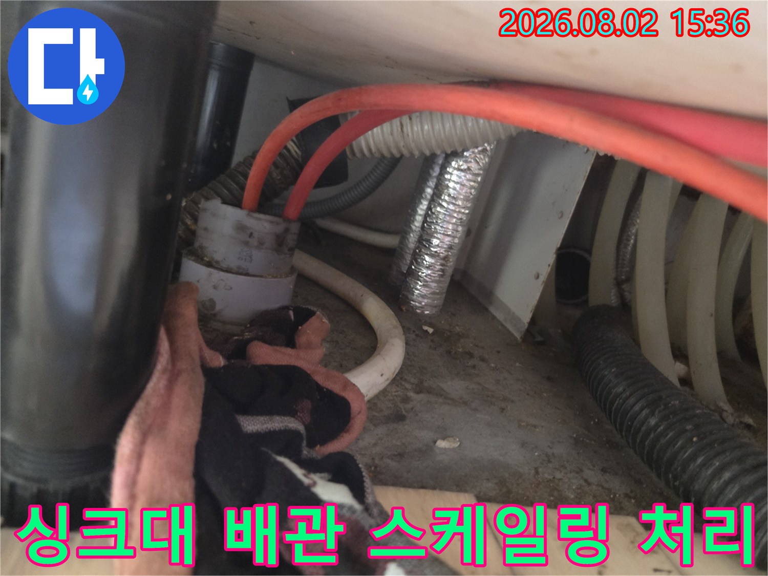샤프트 장비를 활용하여 싱크대 아래쪽 막힌 배관을 청소하는 전문 작업 현장