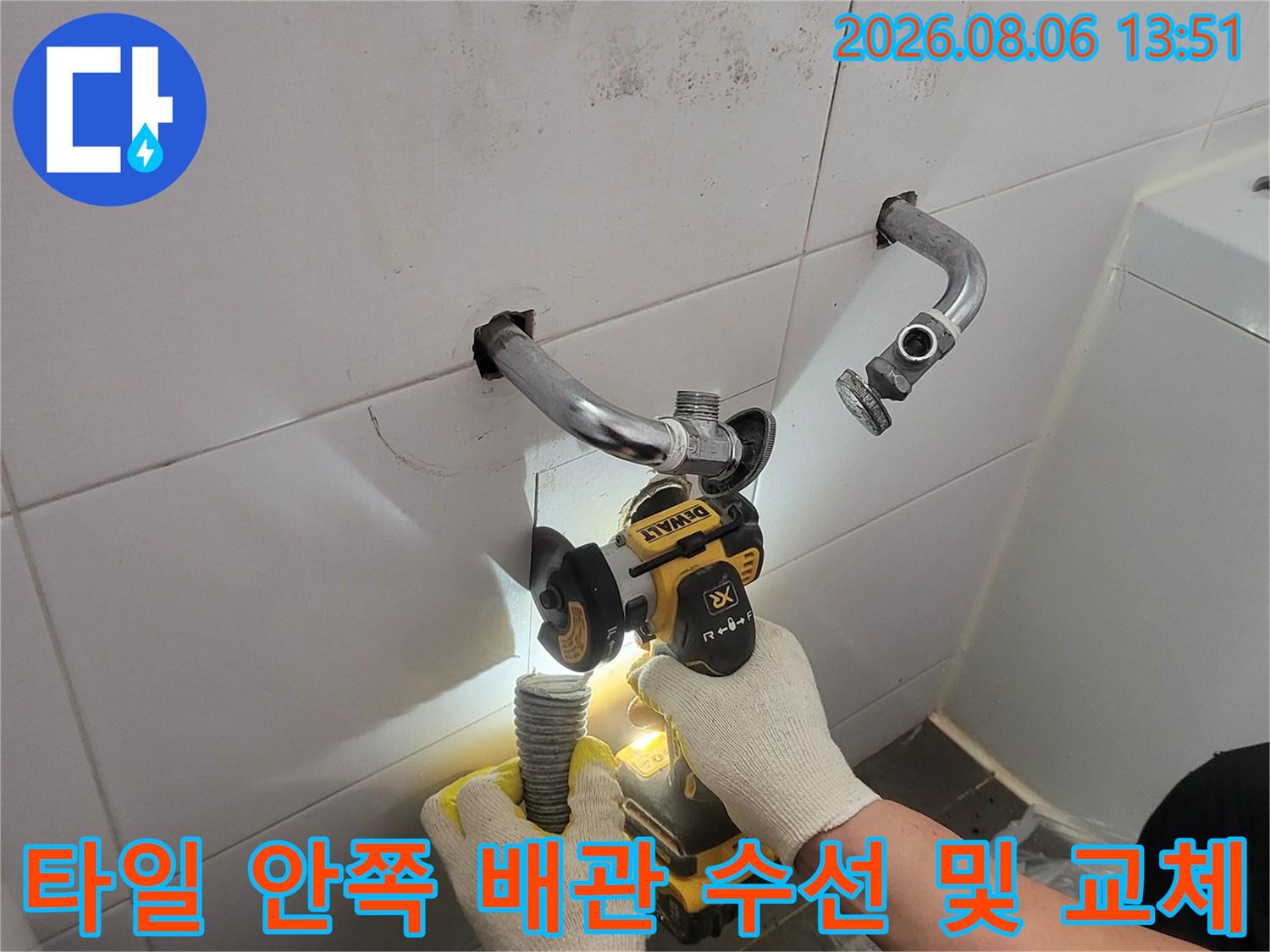 세면대 뒤편 타일 내부의 손상된 배관을 잘라내고 새 부품으로 연결하는 장면