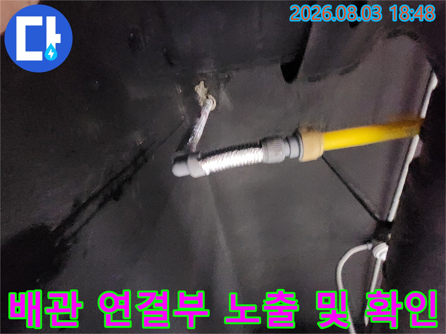 노란색 배관과 은색 호스가 결합된 싱크대 하부의 배관 구간