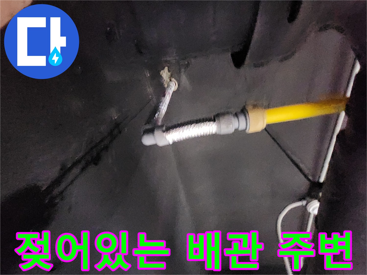 누수로 인해 변색된 벽면과 연결된 노란색 배관의 모습