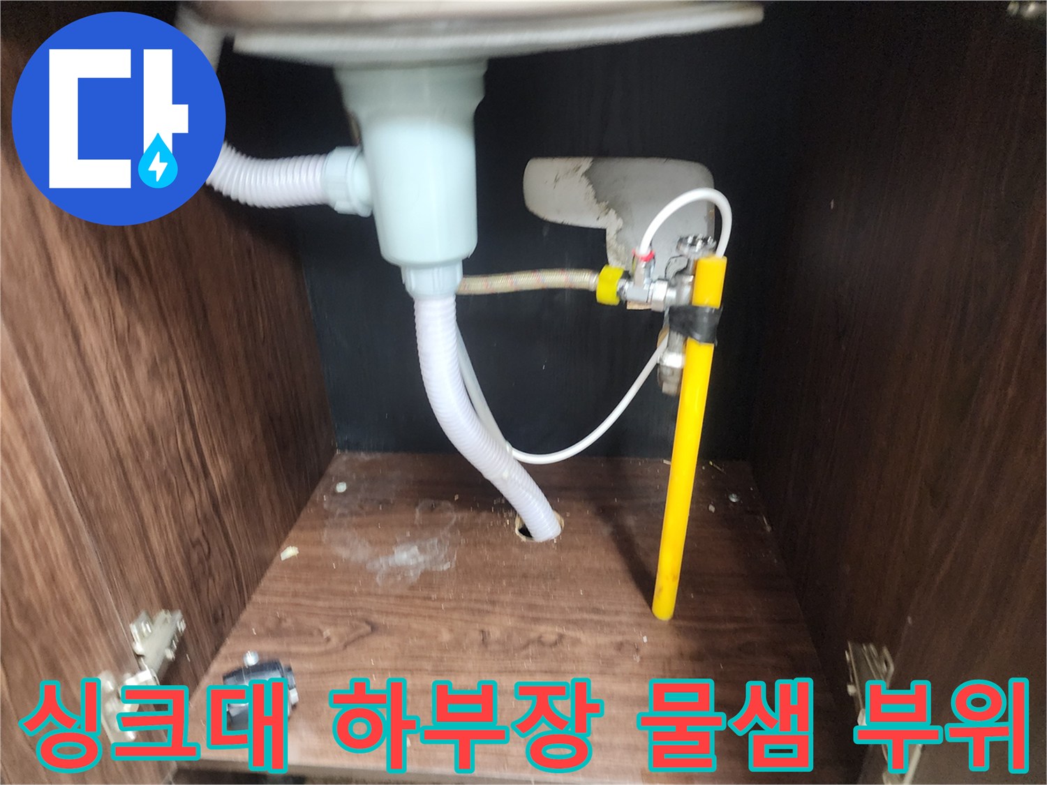 습기로 인해 변색된 싱크대 하부장 바닥재와 배수관 상태