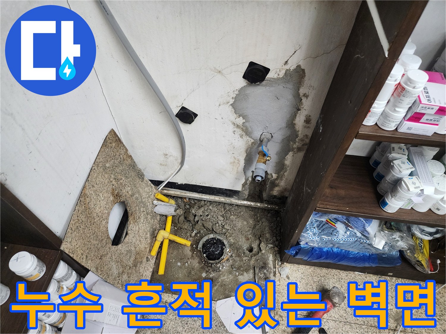 싱크대 밑바닥 배관 주변의 젖은 벽면과 노출된 배수 부속품을 촬영했습니다.