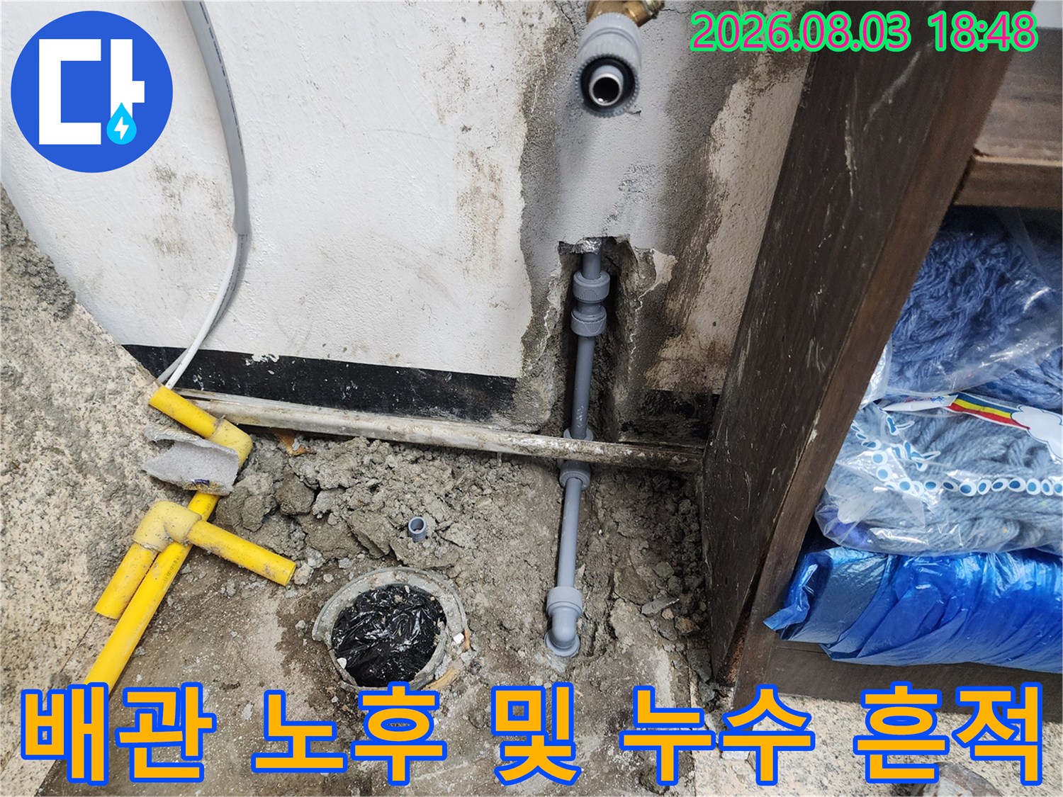 싱크대 하부 공간의 배관 연결 상태와 바닥 습기 오염 부위 사진