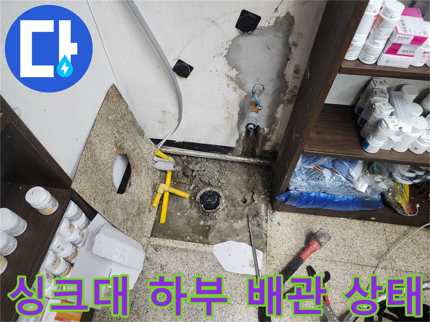 천안 동남구 상가-싱크대 하부장 내부의 노출된 배관과 파손된 벽면 상태