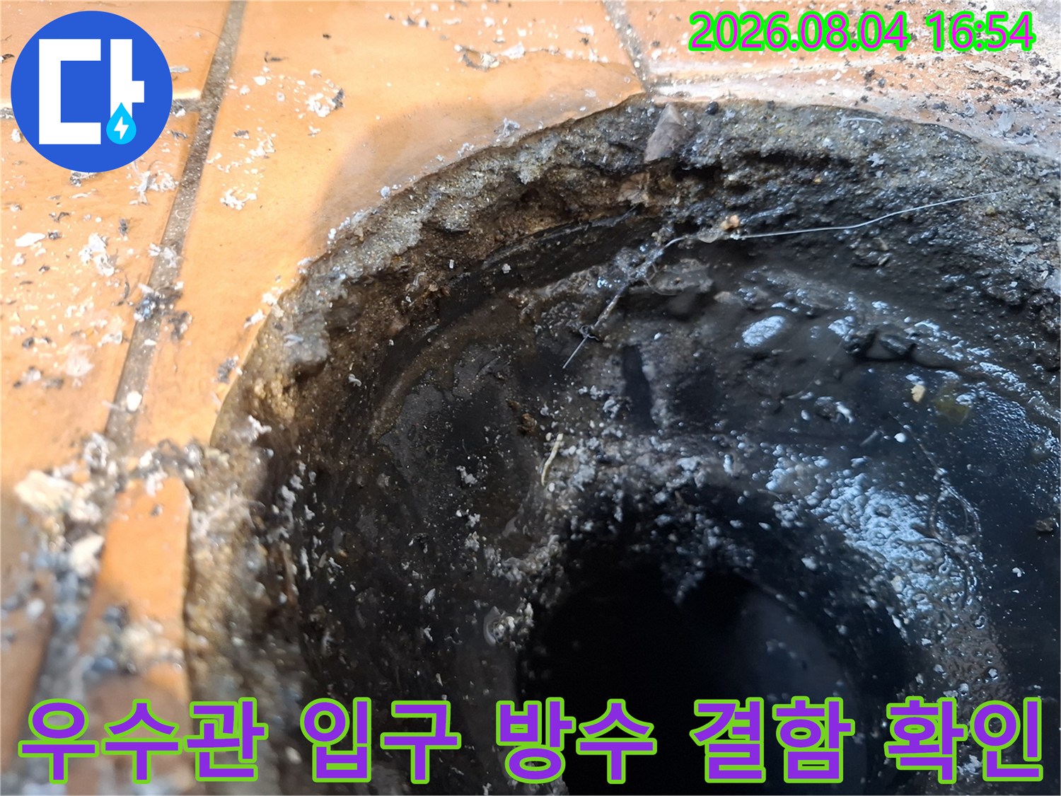 거칠게 마감된 배수구 주변과 어두운 내부를 연결하는 파손된 경계부
