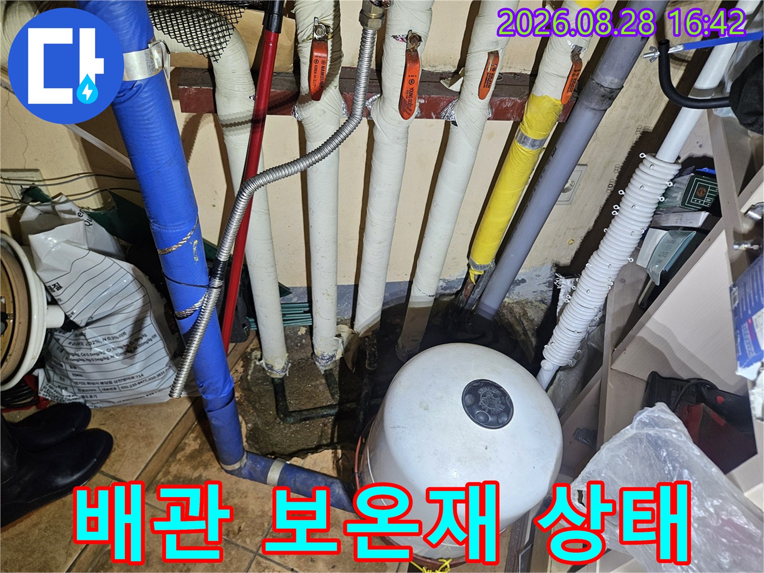 보온재로 마감된 배관들과 흰색 팽창탱크의 근접 촬영 사진입니다.