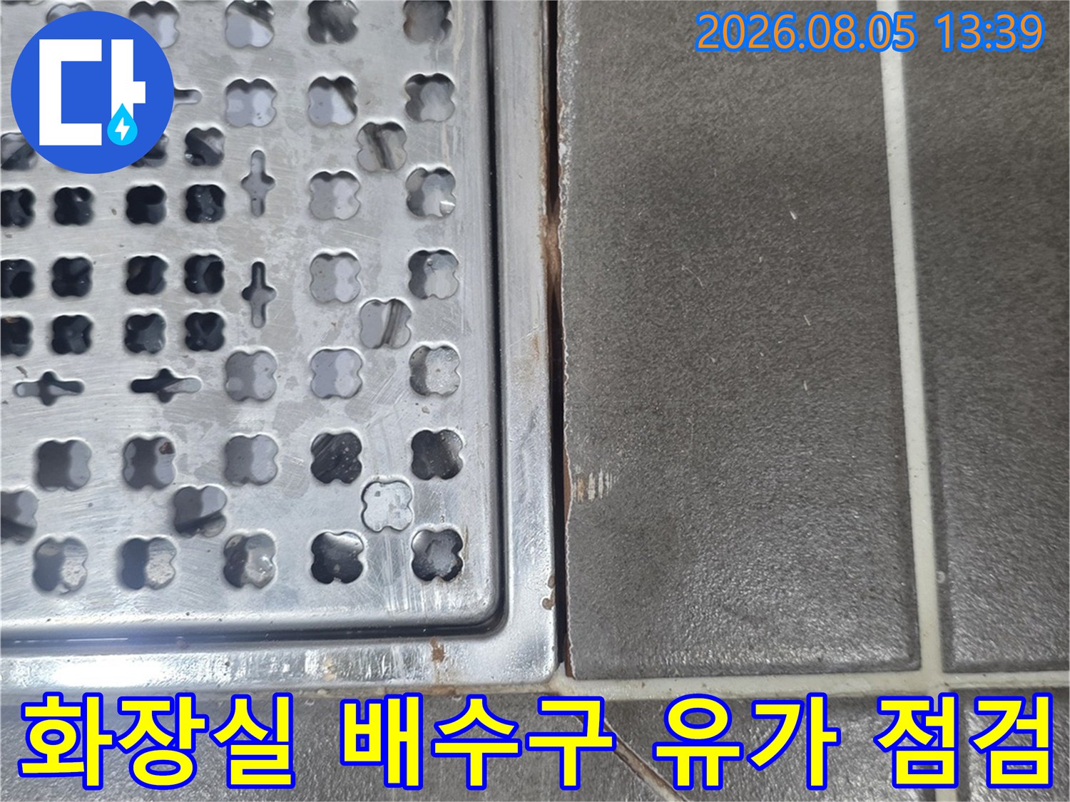 화장실 바닥 배수구 주변의 타일과 금속 유가 프레임 상세 모습