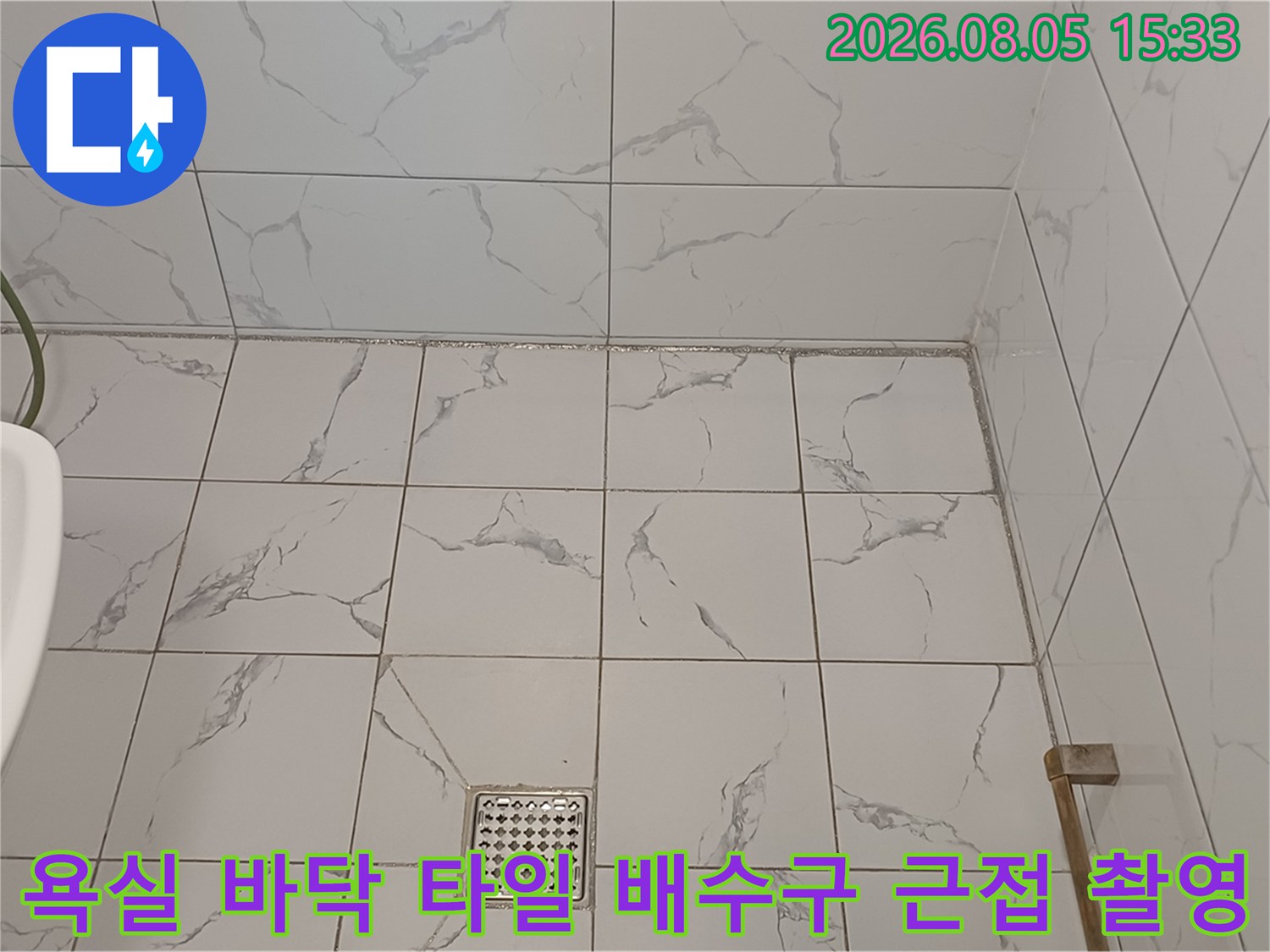 대리석 무늬 타일과 스테인리스 배수구 덮개