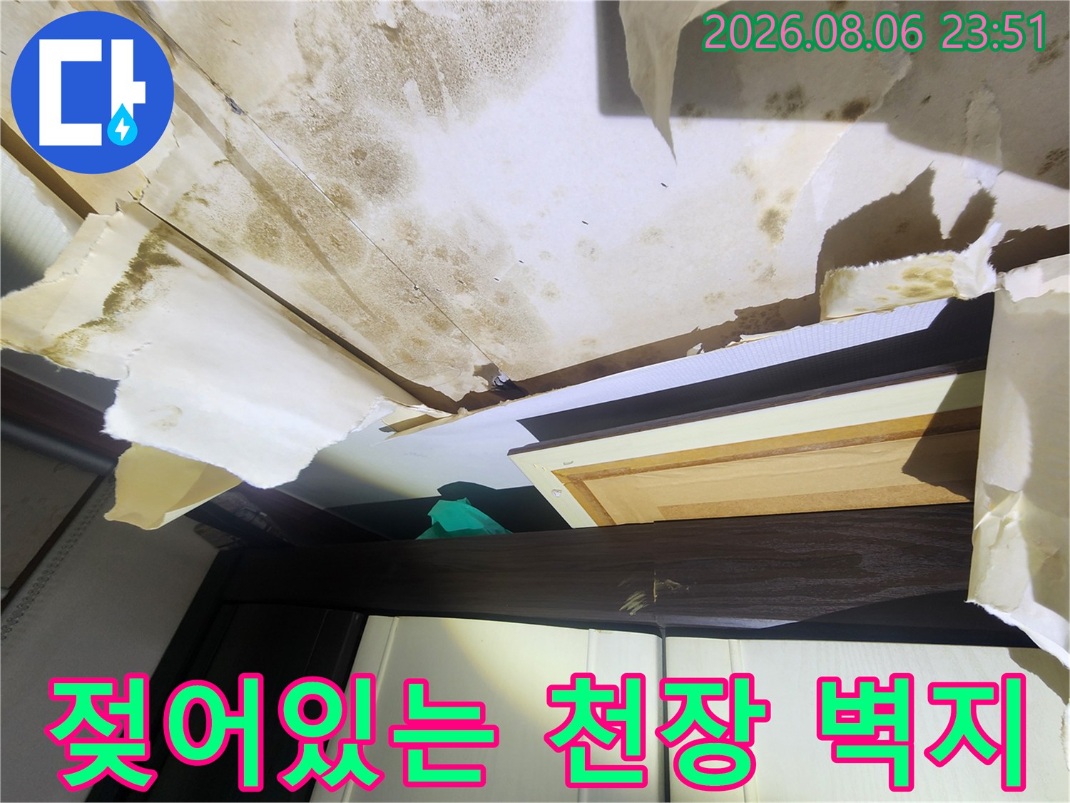 습기로 인해 변색되고 훼손된 천장 벽지 상태를 보여주는 사진입니다.