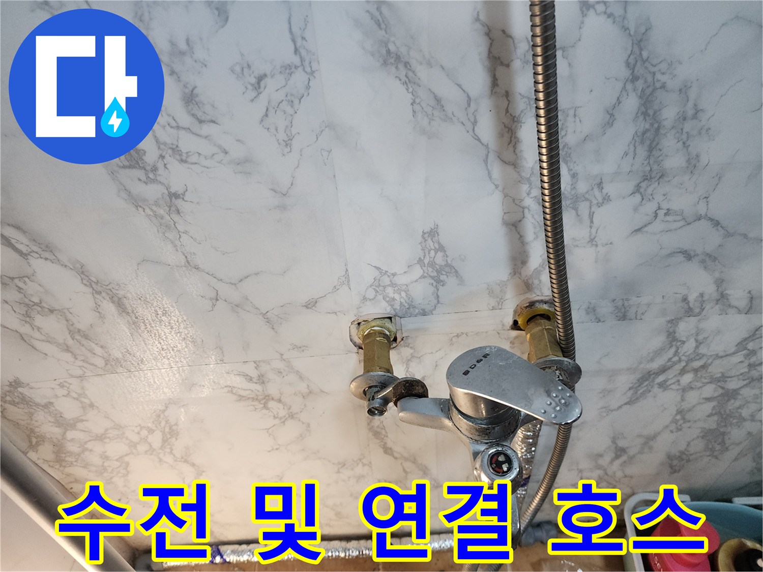 싱크대 수전의 금속 자바라 호스와 벽면 배관의 근접 촬영입니다.