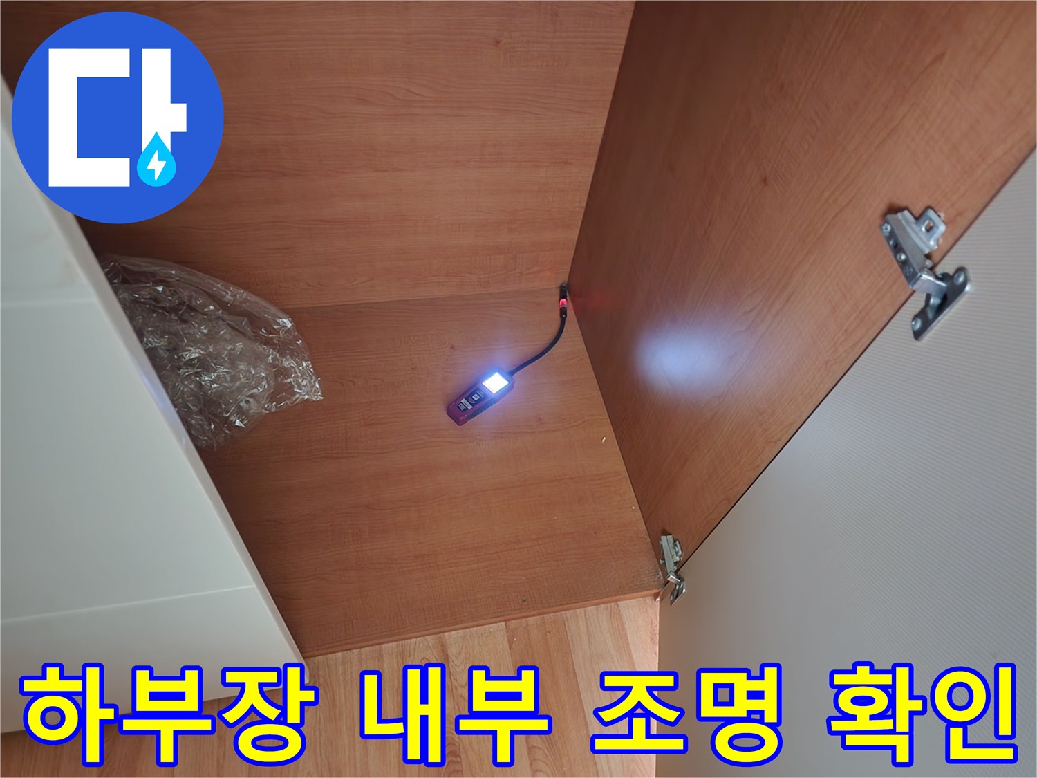 어두운 싱크대 아래쪽을 조명을 이용해 꼼꼼하게 비추며 검사하는 모습