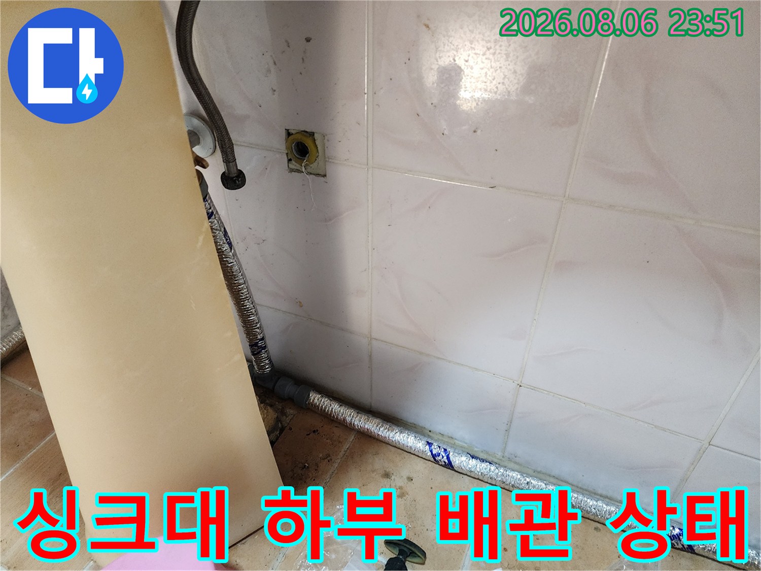 은색 보온재로 감싸진 배관과 벽면 타일의 연결 부위 사진입니다.