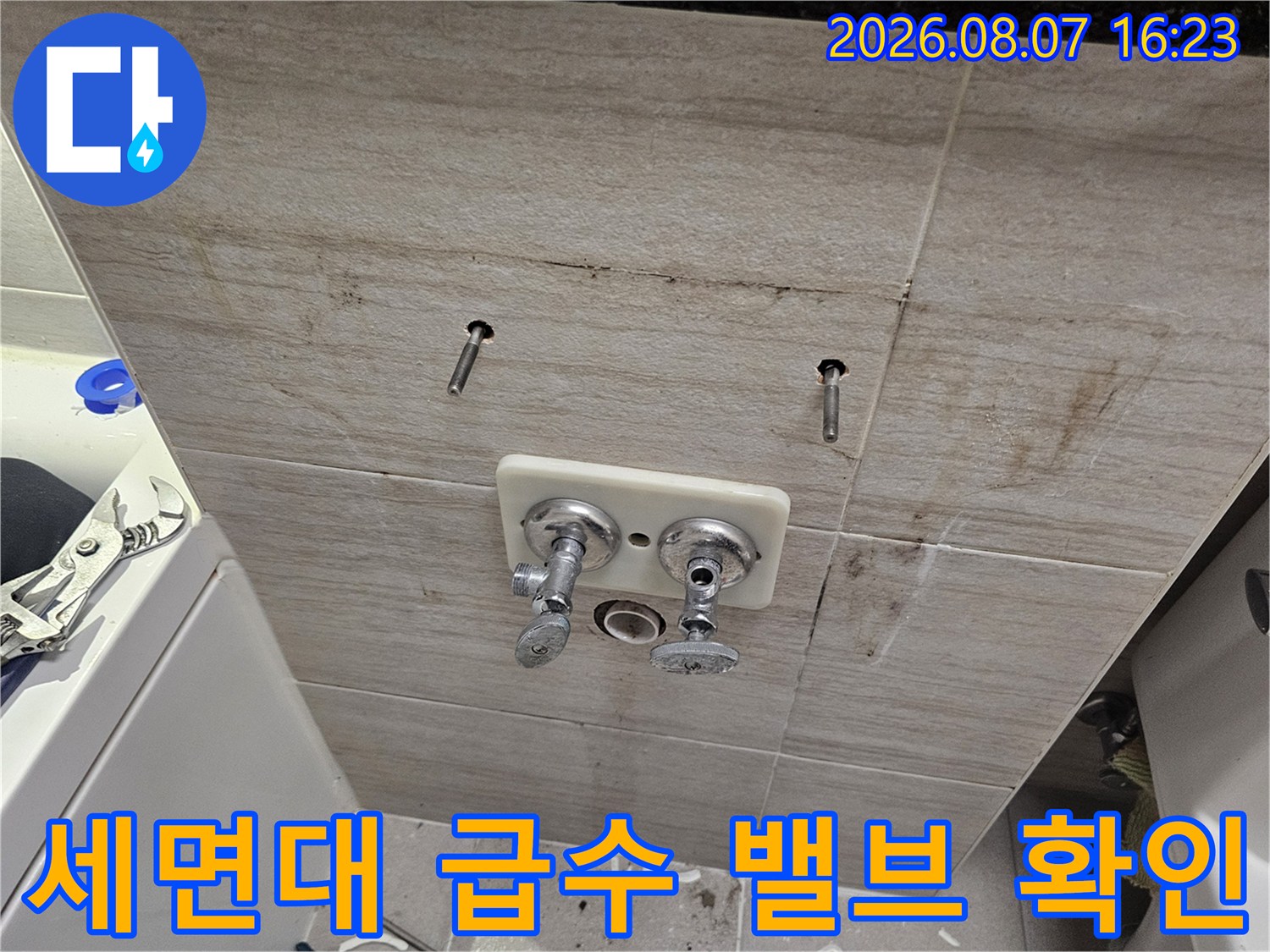 벽면에 고정된 세면대용 수전 연결 부위와 타일 벽면