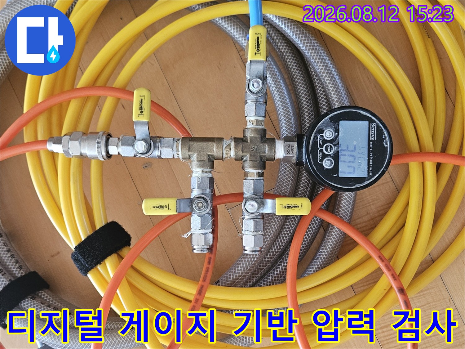 금속 밸브와 노란색 호스가 연결되어 디지털 화면에 수치가 표시된 장비 사진