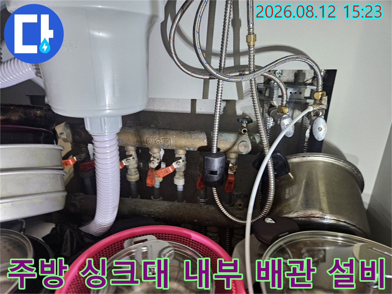 흰색 정수기 필터 장치와 금속제 유연 호스들이 복잡하게 연결된 주방 하단부 전경