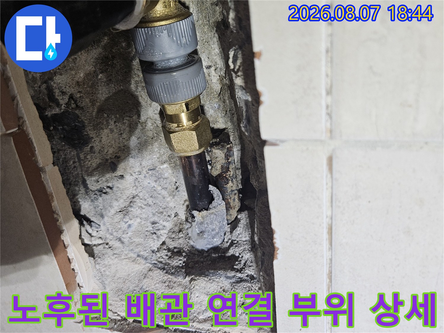 습기를 머금은 콘크리트 사이로 노출된 수도 배관의 결함 상태를 보여줍니다.