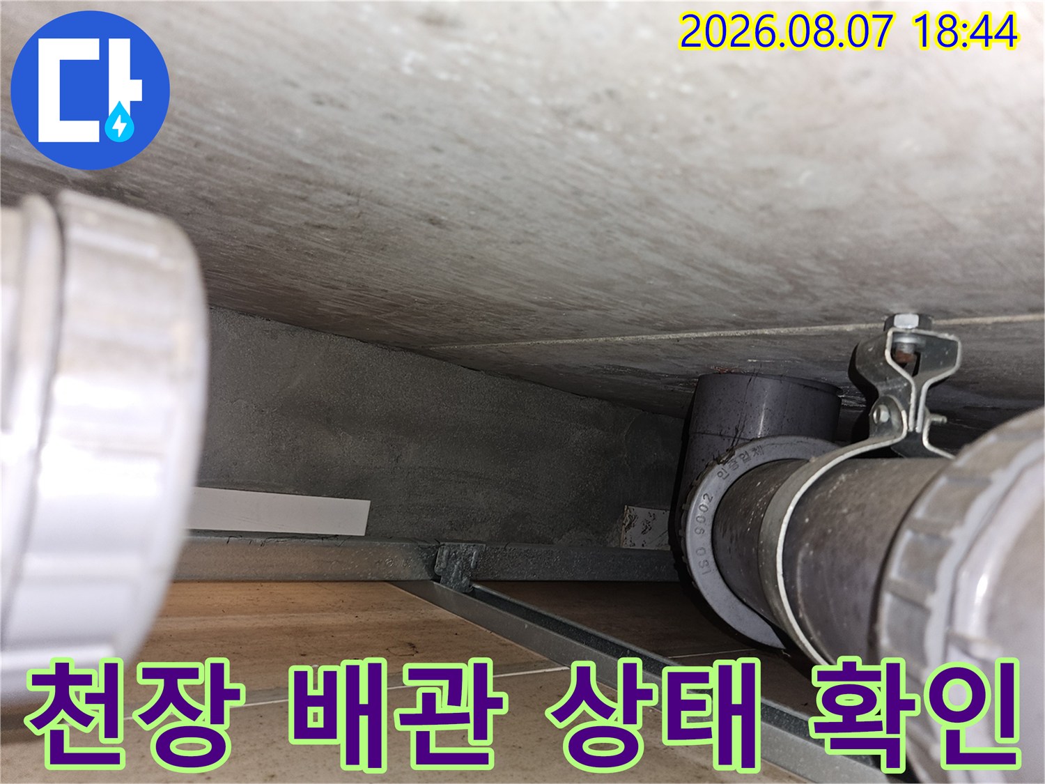 아파트 천장 내부의 검은색 배관과 하수관 연결 부위 근접 촬영