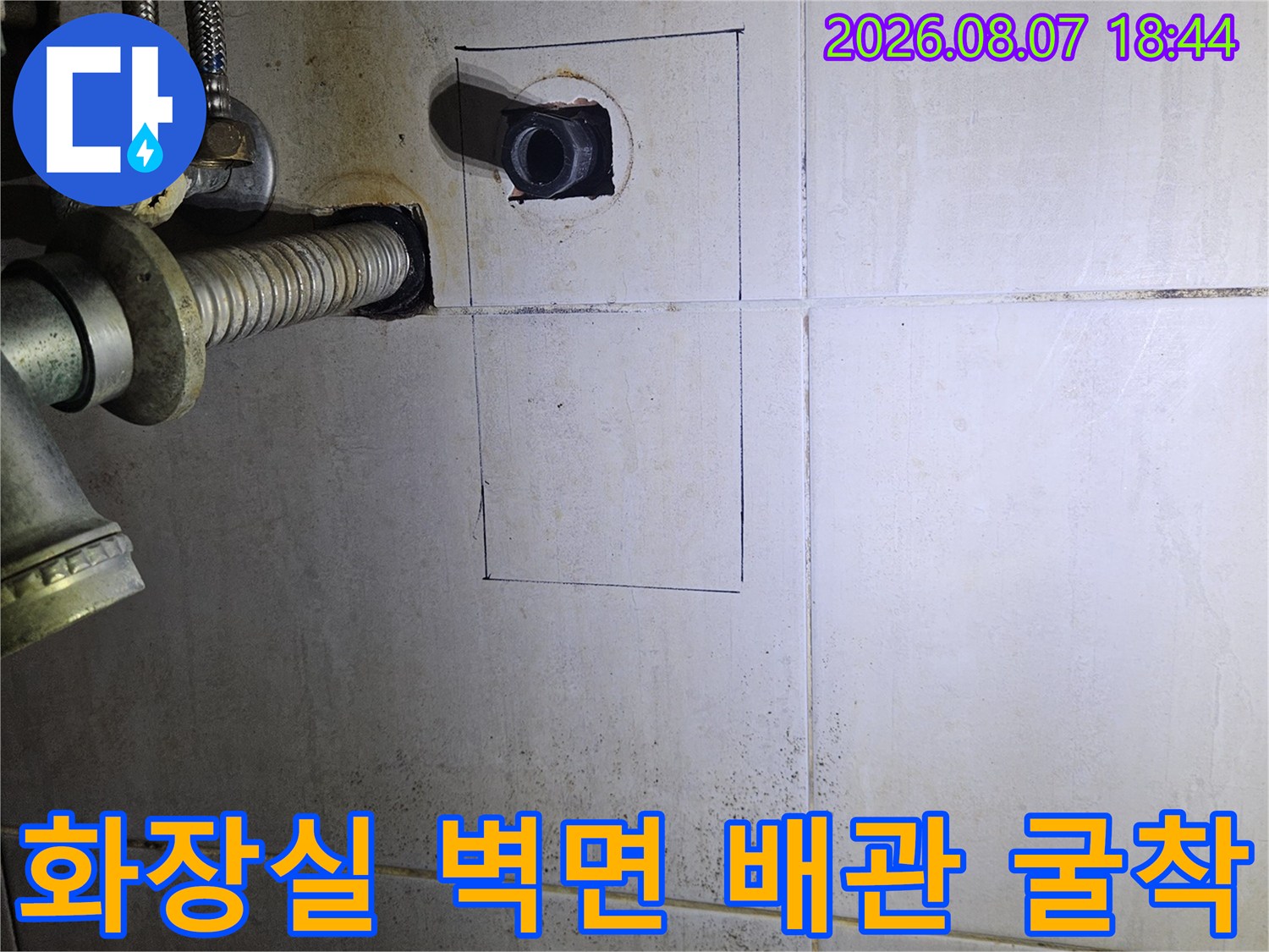 타일을 사각형으로 제거하여 내부 매립 배관을 점검하는 현장 모습입니다.