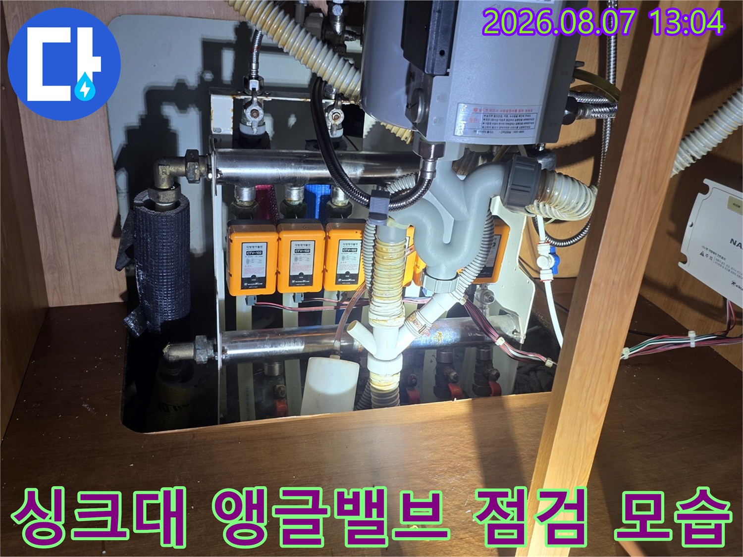 싱크대 하부의 앵글밸브와 급수 배관 연결 부위를 점검하는 장면입니다.