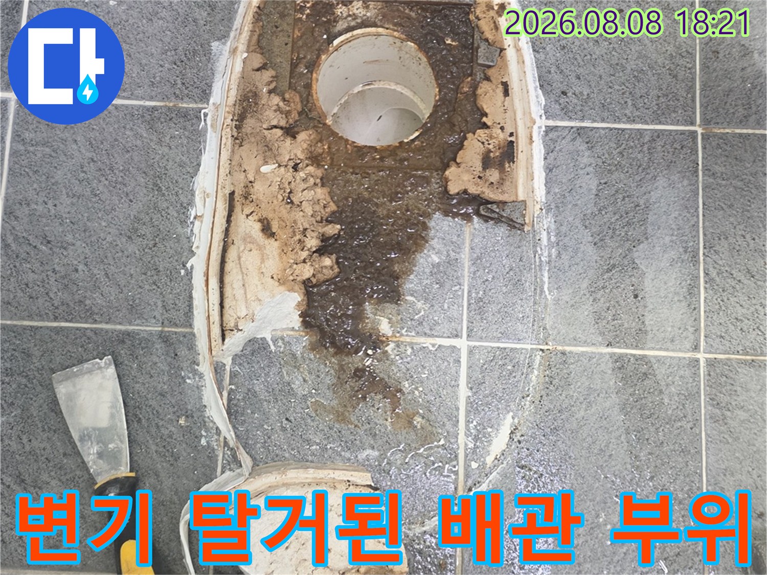 변기를 제거하여 드러난 오염된 배관과 타일 파편
