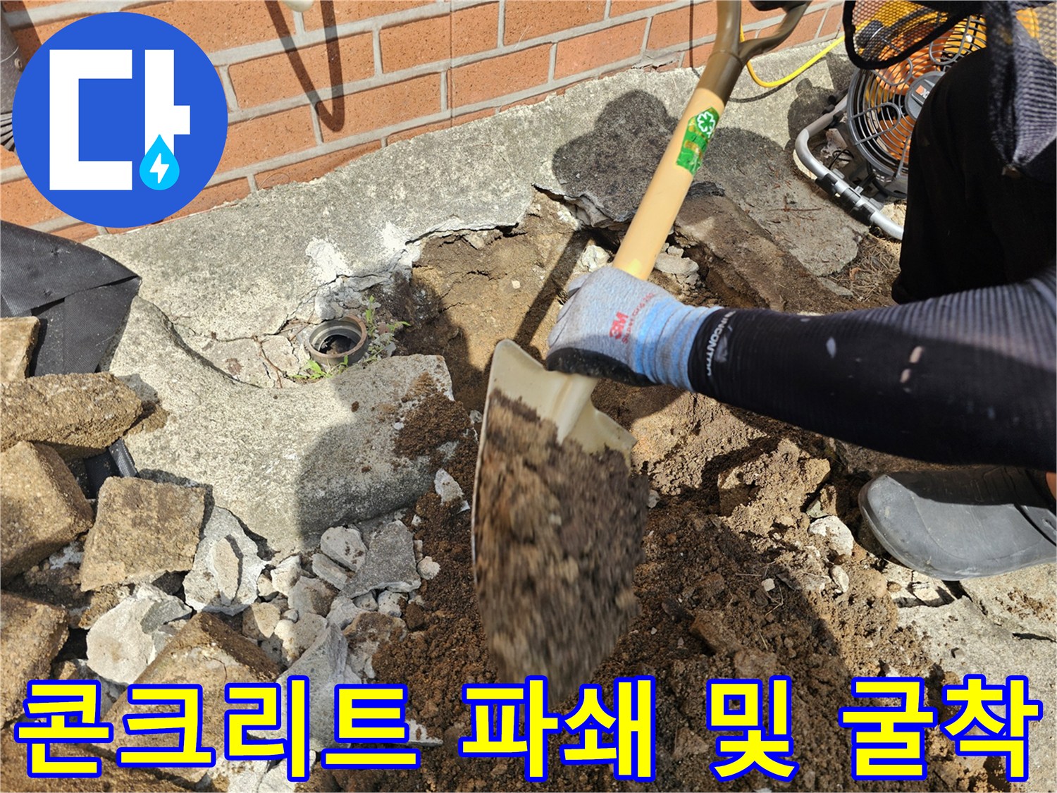 삽을 사용하여 콘크리트 파편과 흙을 제거하며 배관을 노출시키는 작업