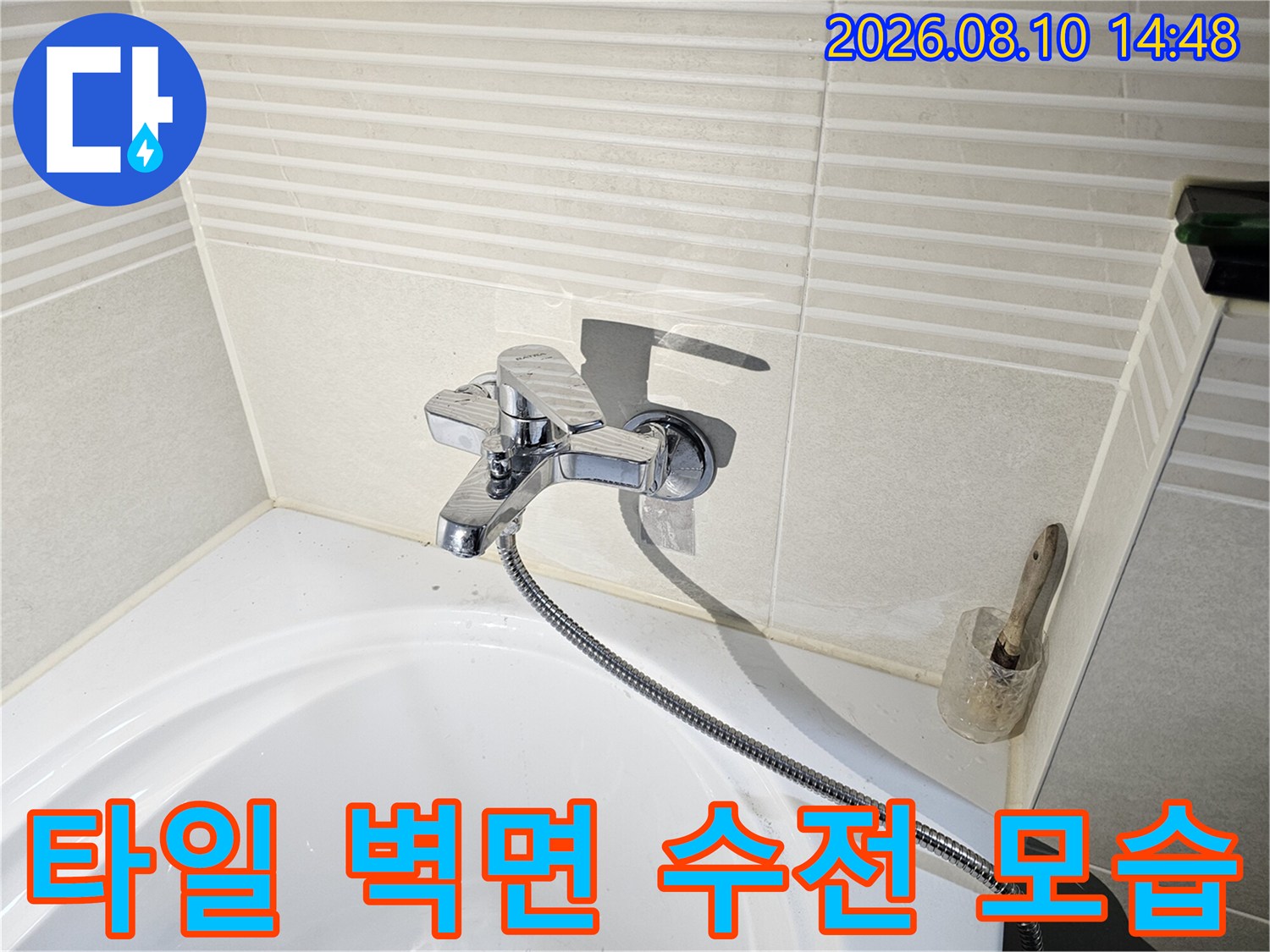 화장실 타일 벽면에 설치된 욕조용 수전과 샤워기 호스 상세 사진입니다.