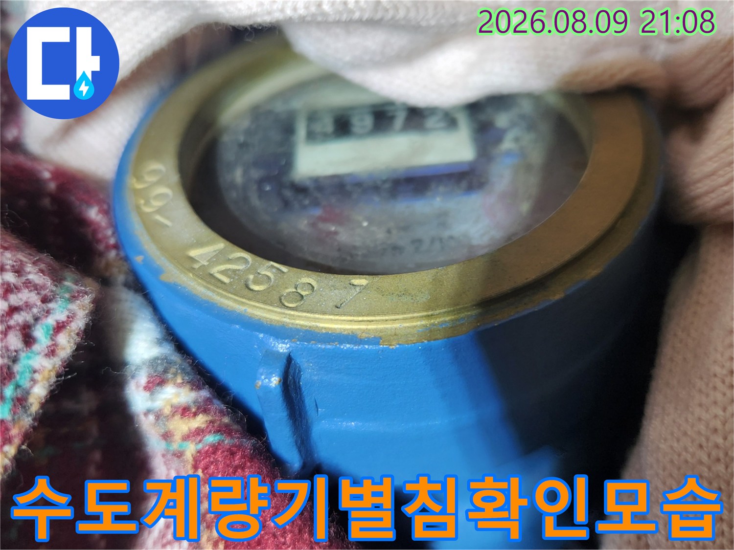 파란색 수도 계량기의 숫자가 적힌 창과 별침 부분을 촬영한 사진