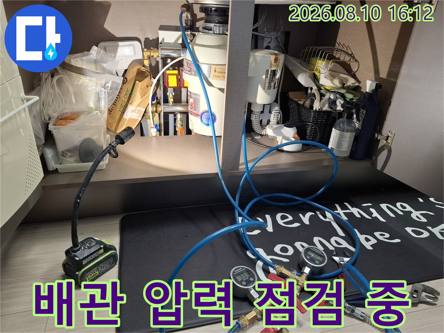 싱크대 하부 배관 연결부에 설치된 압력 게이지와 파란색 호스