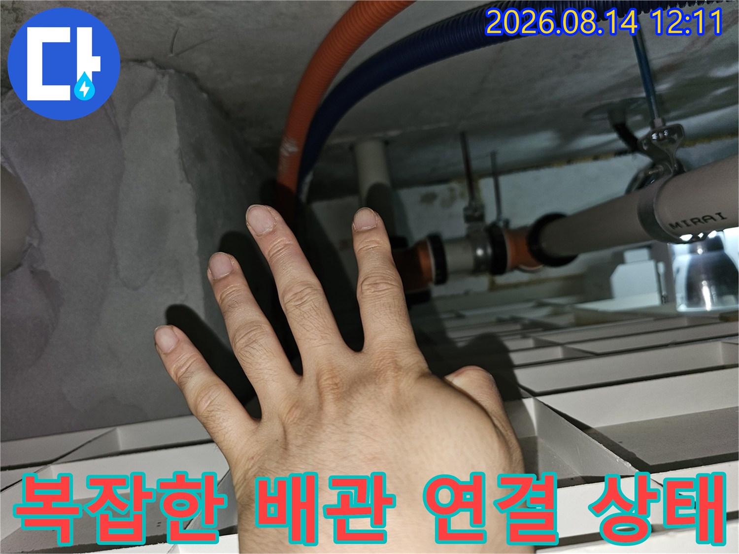 싱크대 하부 천장에 설치된 오렌지색과 파란색 주름관 점검