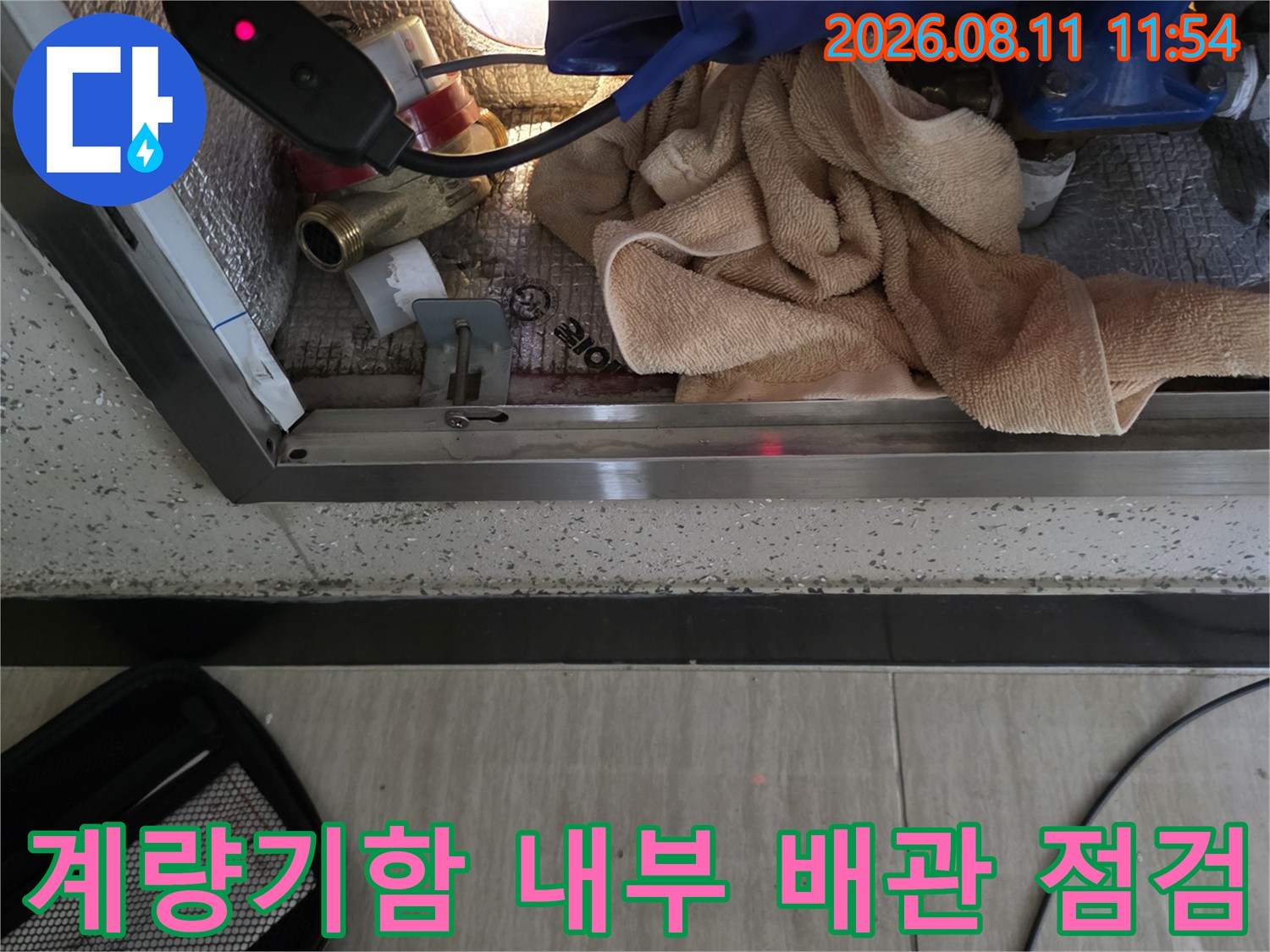 좁은-계량기함 공간 내부에 장비를 투입하여 배관의 누수 여부를 확인하는 모습입니다.