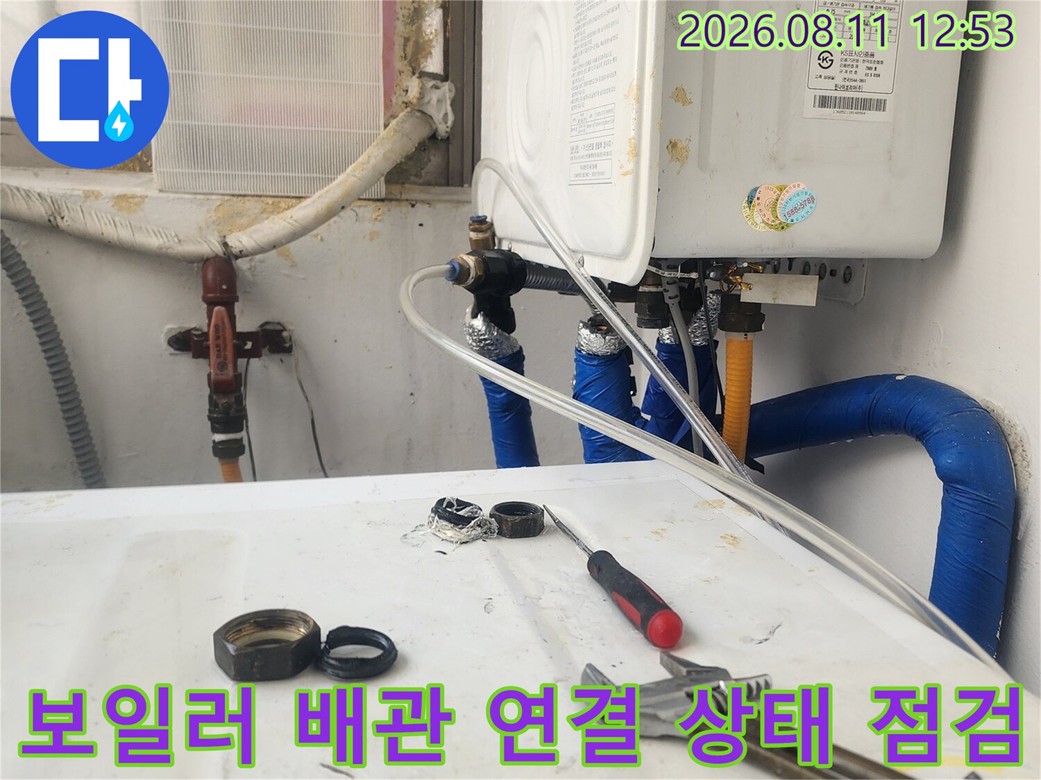 보일러 하단의 파란색 보온재로 덮인 배관과 밸브를 촬영한 사진