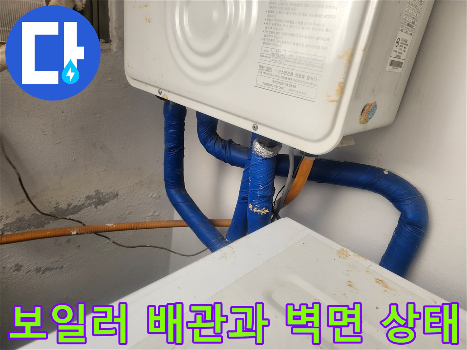 보일러 하부의 파란색 보온재로 감싸진 배관과 노후된 벽면 모습