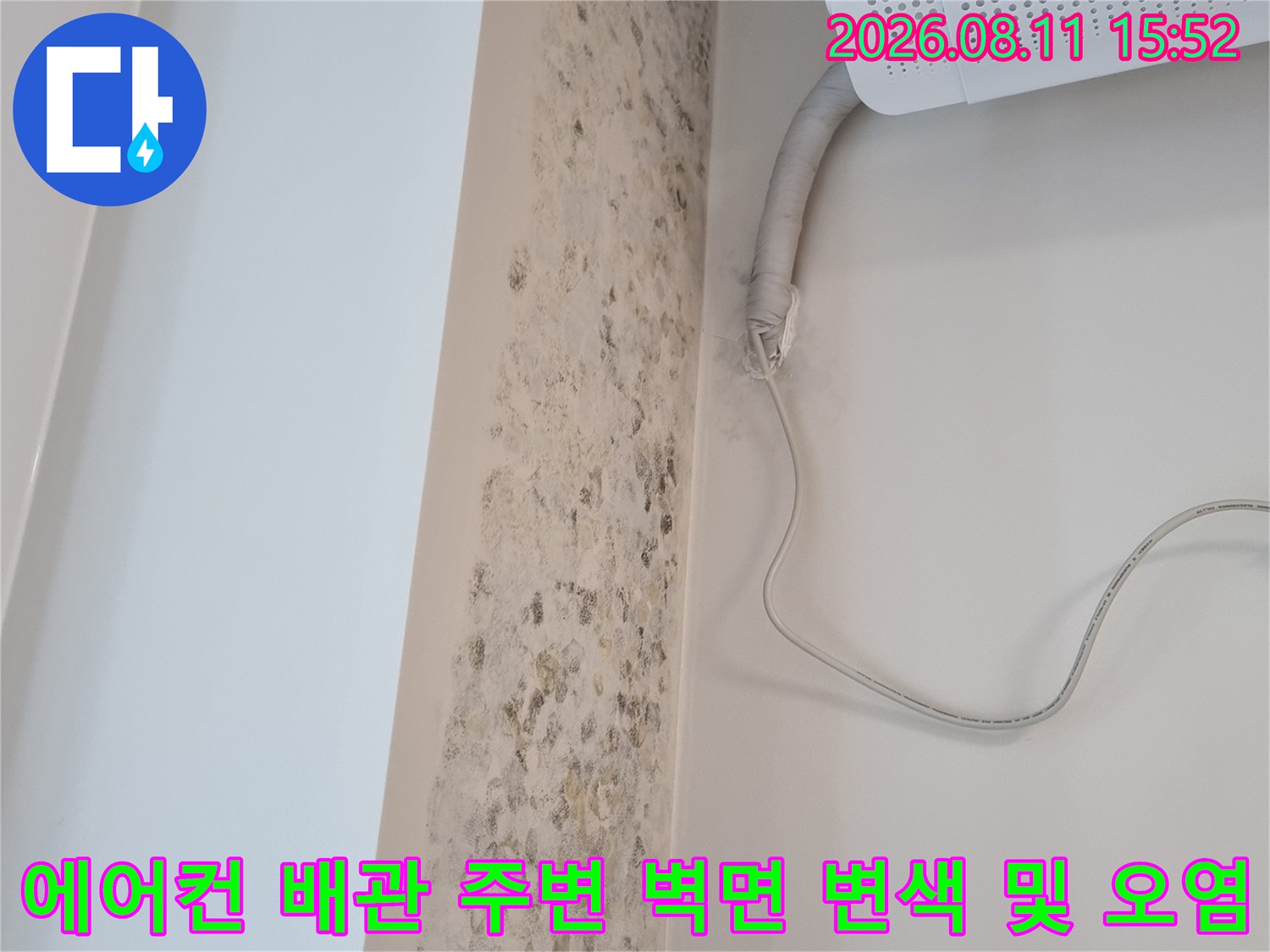 흰색 에어컨 실내기와 연결된 호스 아래쪽으로 퍼진 갈색의 누수 곰팡이 흔적